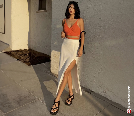 Model wearing an orange crop top and white skirt